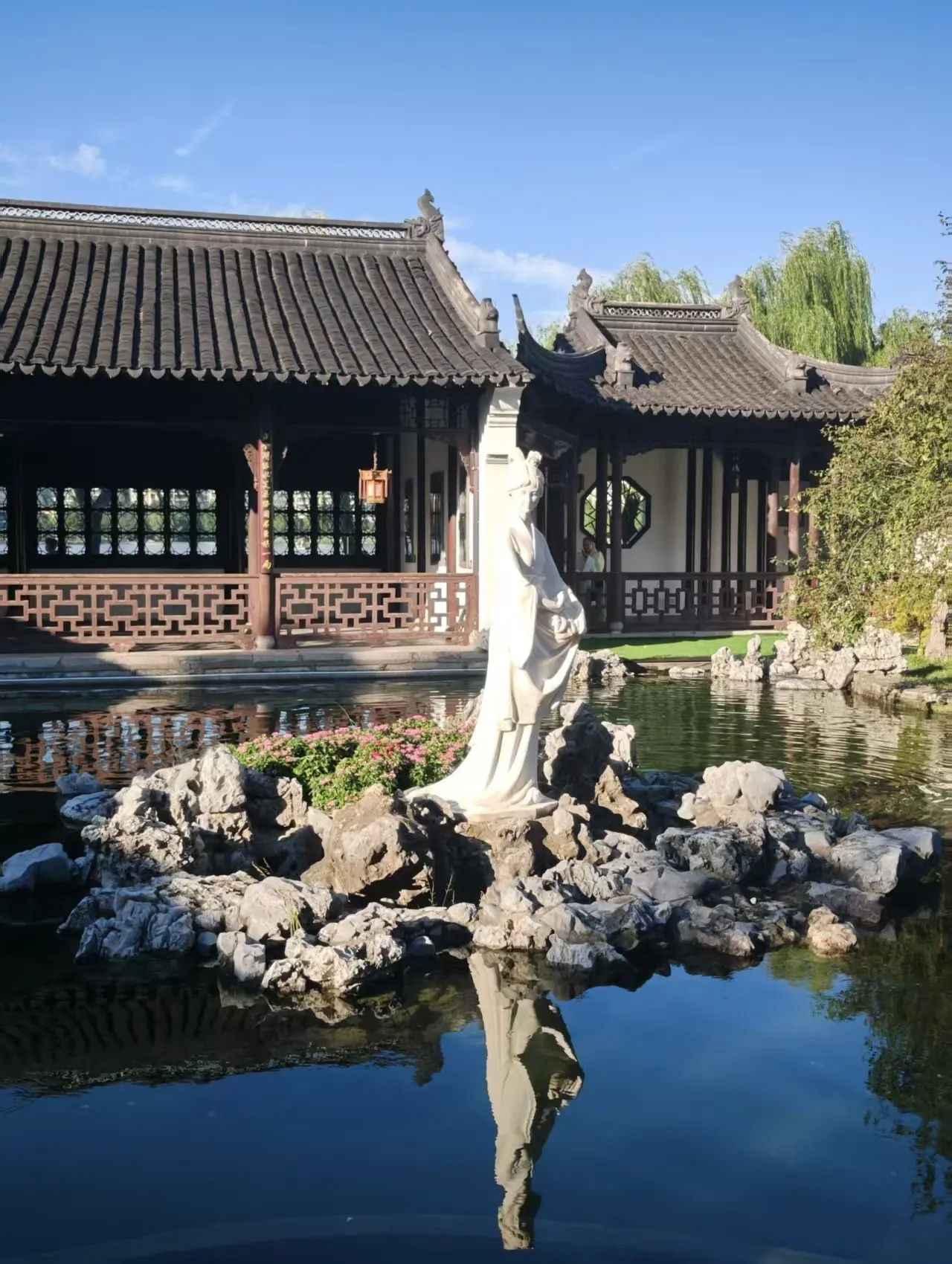 池畔白色石像与层叠的屋檐